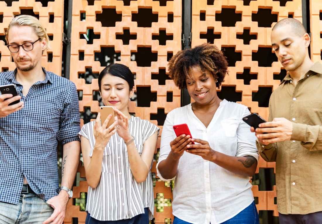 four people holding mobile phones